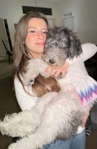 Young woman hugging two small dogs indoors.